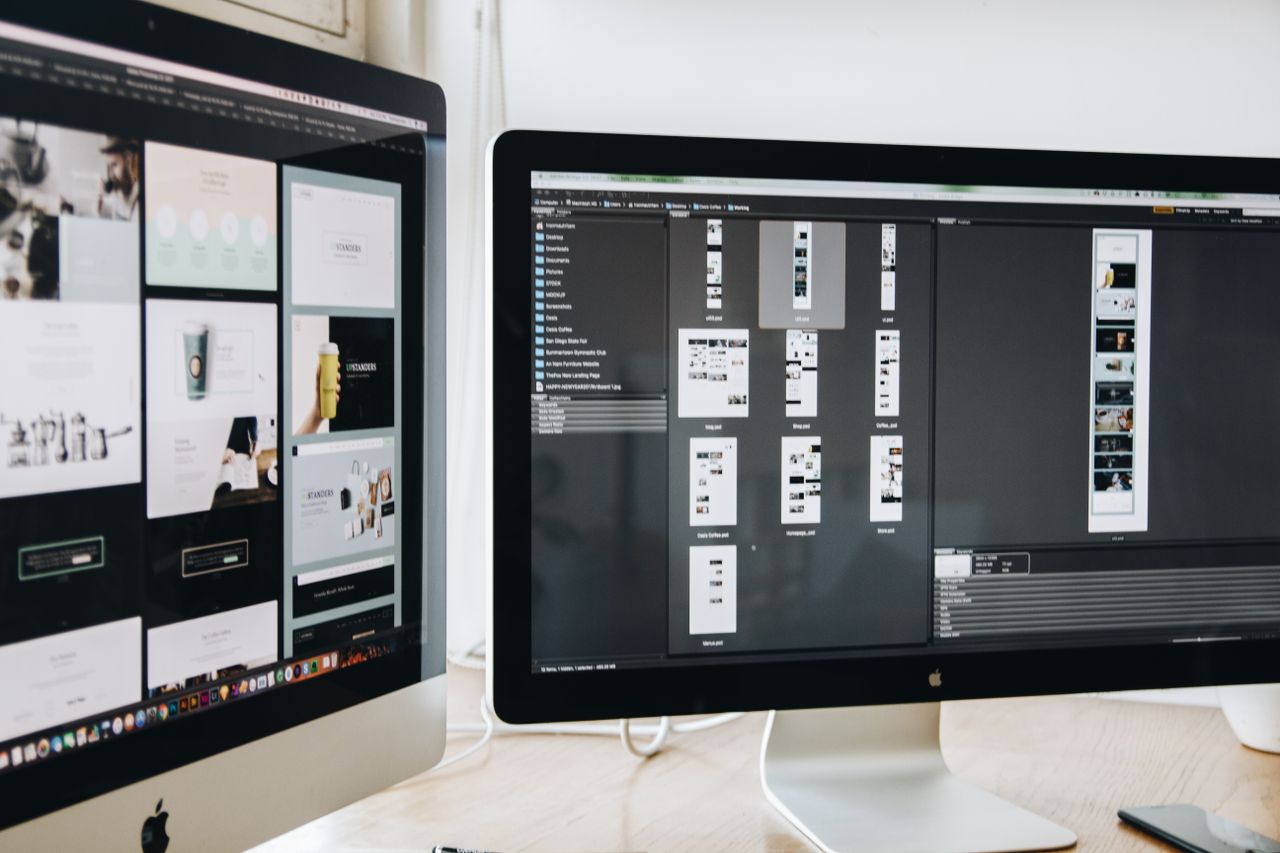 Un espace de travail contemporain doté de deux écrans d’ordinateur montrant des projets de web design, mettant en avant la technologie et la productivité.